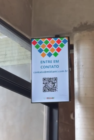 Tela vertical com QR code de contato instalada em entrada comercial