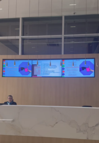 Três telas em videowall na recepção de um edifício corporativo